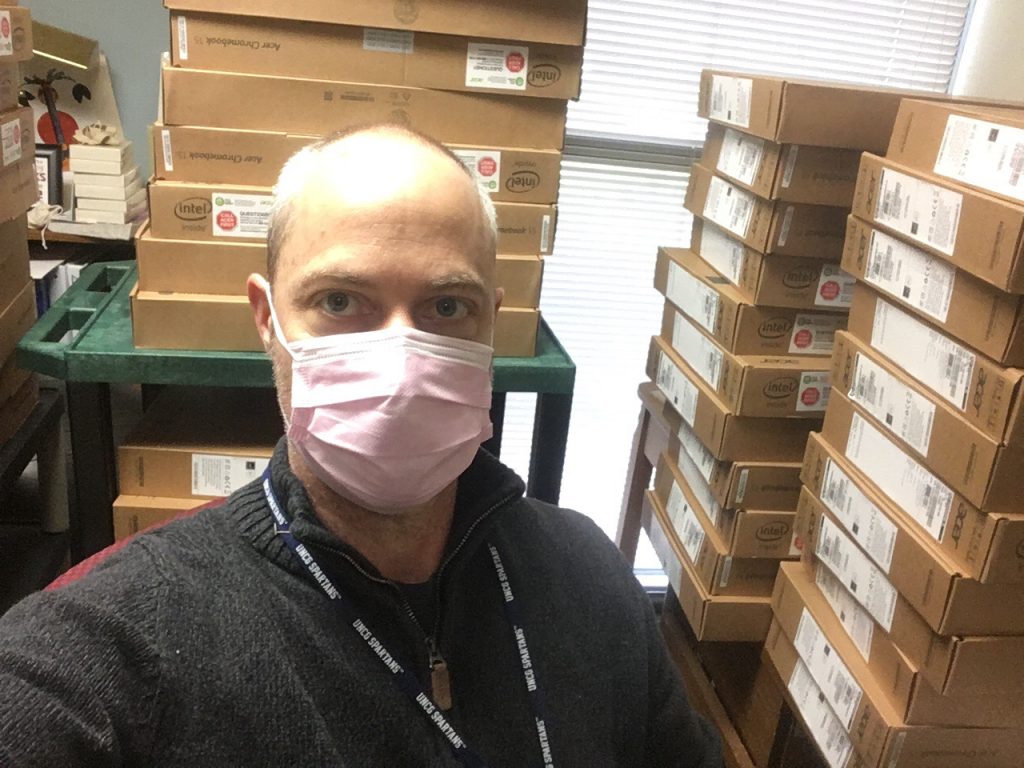 Stephen wearing a mask in front of boxes of chromebooks.