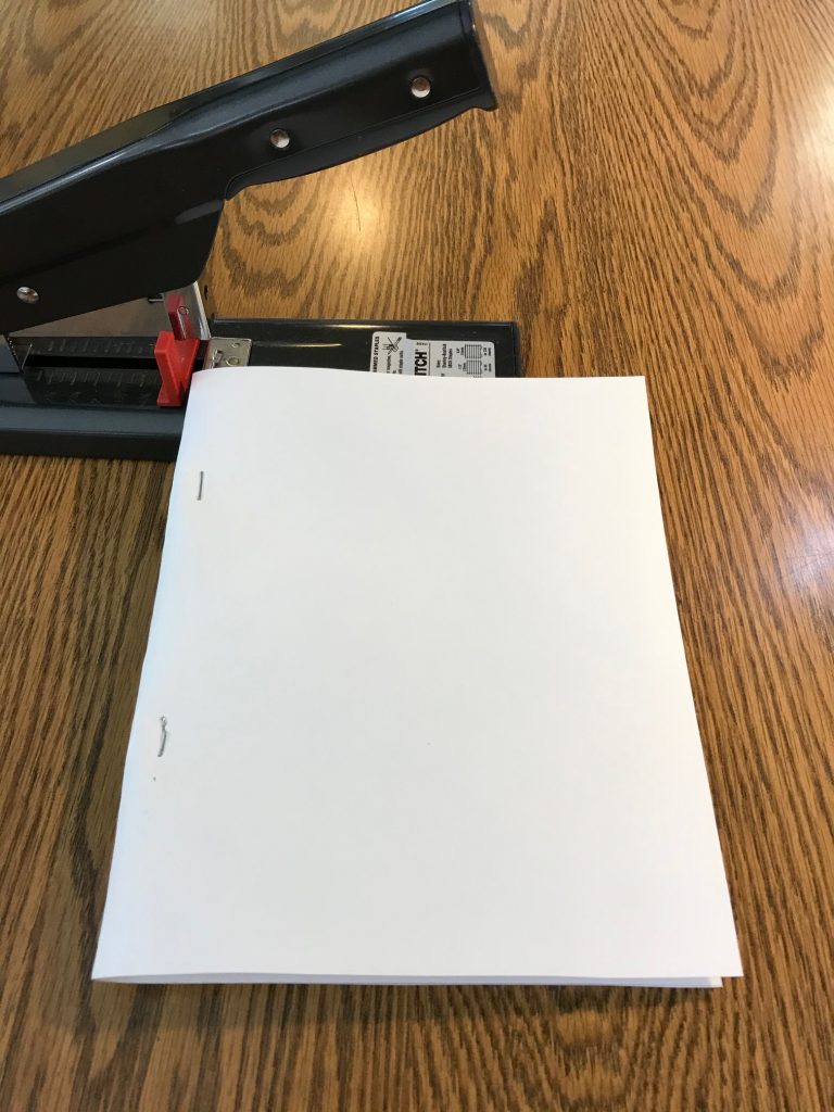 A stapler and the cover fastened to the booklet with two staples