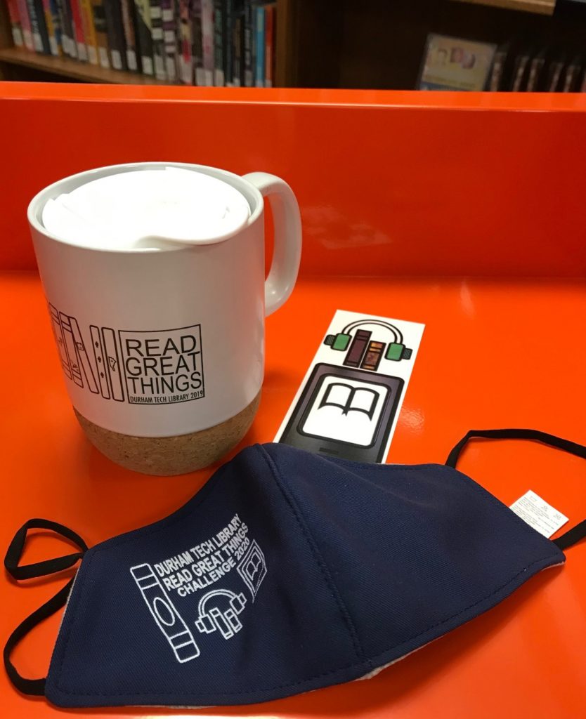 white ceramic coffee mug with tan cork bottom and white plastic lid, navy blue face mask with black elastic ties, and a bookmark peeking out, all with Read Great Things logos on them