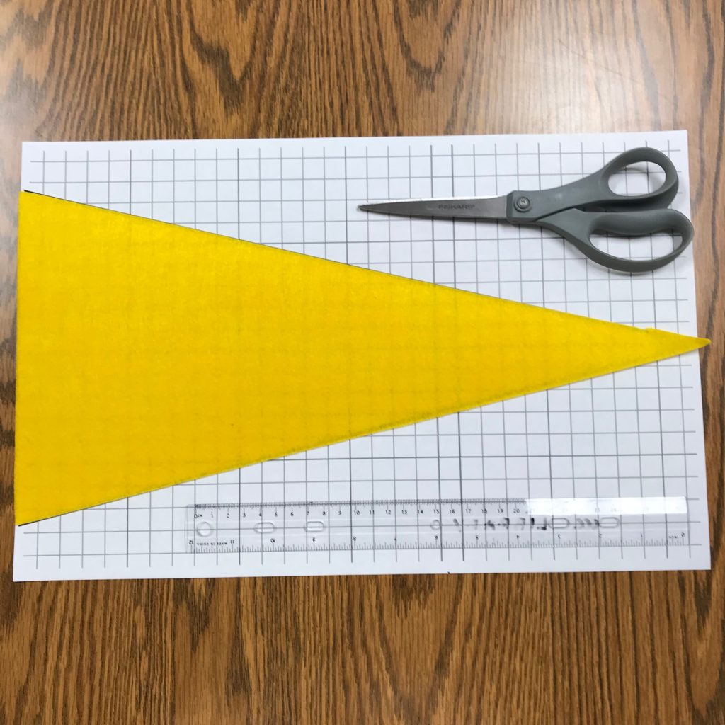 yellow felt triangle banner/pennant on graph paper with scissors and ruler